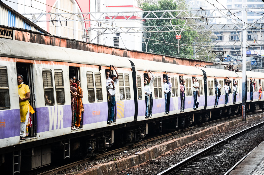 Commuter trains in Mumbai are often so packed with passengers that people hang out the doors.  When the trains are at more reasonable capacity, people hang out the doors anyway.