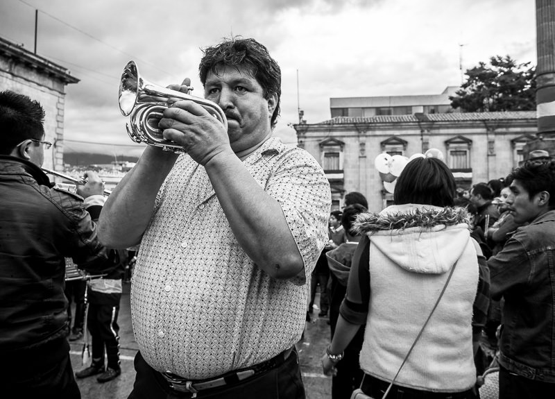 Man playing a small horn in a Guatemalan independence parade in Xela. Guatemalan Independence & Xela Feria 2014 - GreatDistances / Matt Wicks