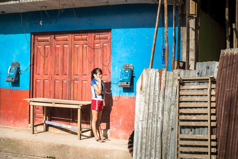 Girl uses a public phone in Nauta, Peru. Backing up photos while backpacking - GreatDIstances / Matt Wicks