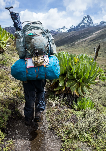 man carrying two backpacks simultaneously on Mount Kenya. GreatDistances / Matt Wicks