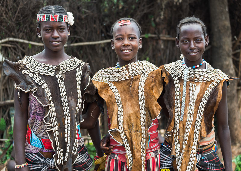 Key Afer market, three Benna tribe girls in goatskins and puka shells. Photographing the Tribes of South Omo, Ethiopia - GreatDistances / Matt Wicks